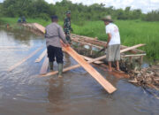 Gotong Royong Atasi Banjir Lokal, Bhabinkamtibmas Tumbang Nusa Bantu Warga Bangun Jembatan Darurat